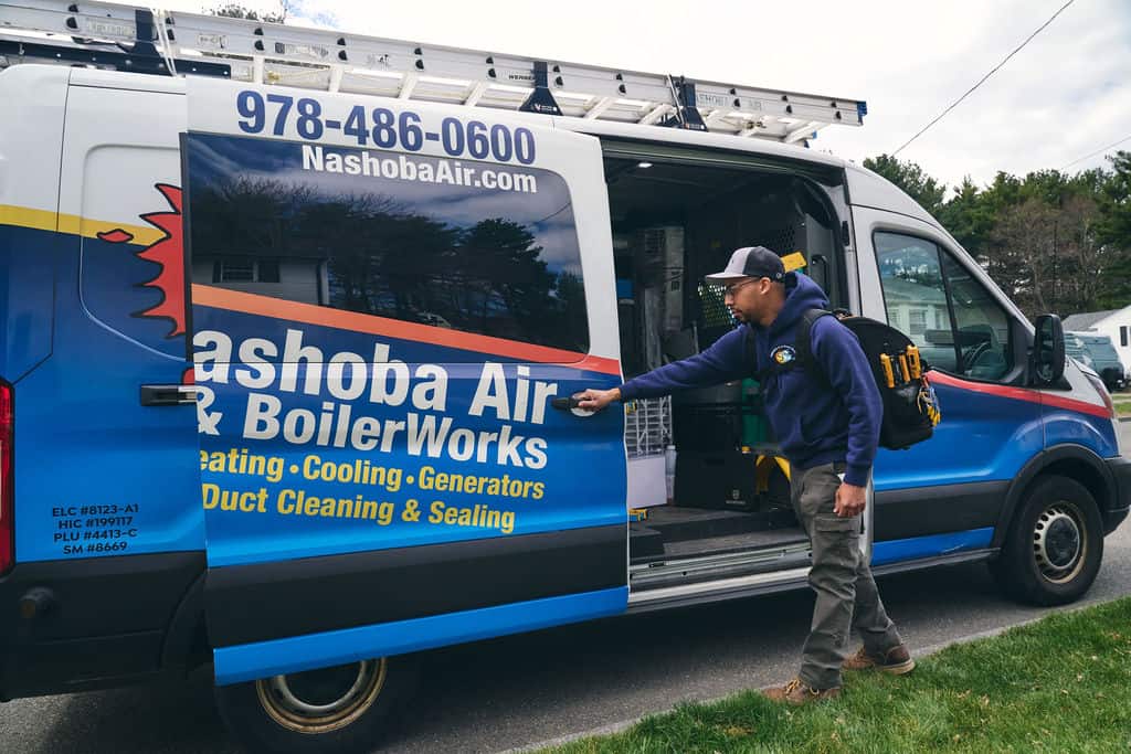 A technician opens the side door of a Nashoba Air & BoilerWorks service van parked on a suburban street, ready to provide expert AC Repair & Cooling Services.
